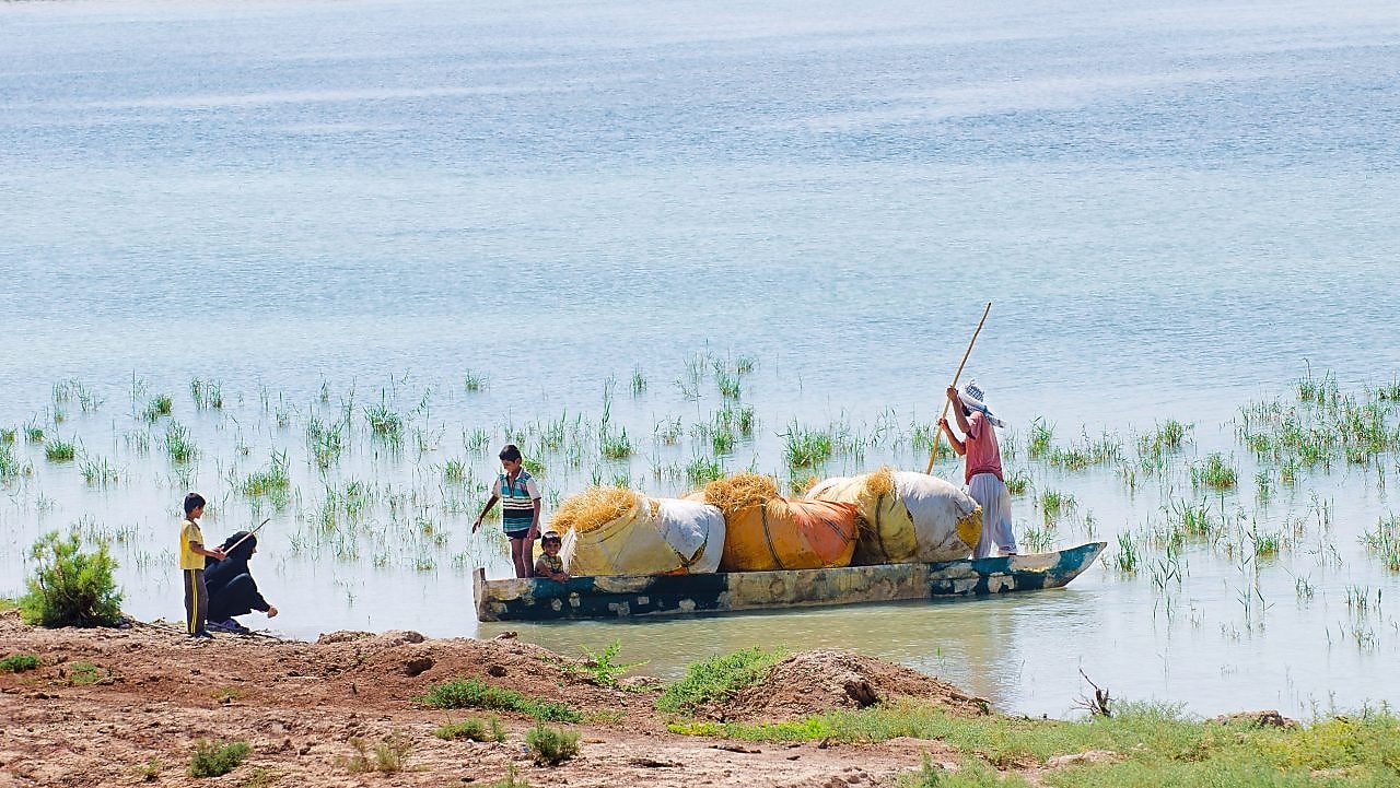 السكان المحليون يعبرون هور الحويزة الذي تغمره المياه بالقرب من مشروع ماجنون في العراق