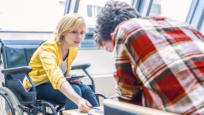 سيدة على كرسي متحرك تتحدث إلى رجل