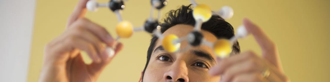 شاب يتفحص نموذج جزيئي