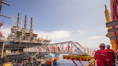 عمال يعبرون إلى منصة جديدة بنيت جنبا إلى جنب مع مشروع مالامبايا في المياه العميقة 