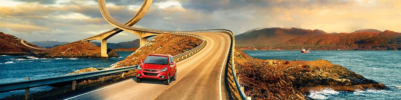 سيارة حمراء تسير على طريق بجوار نهر