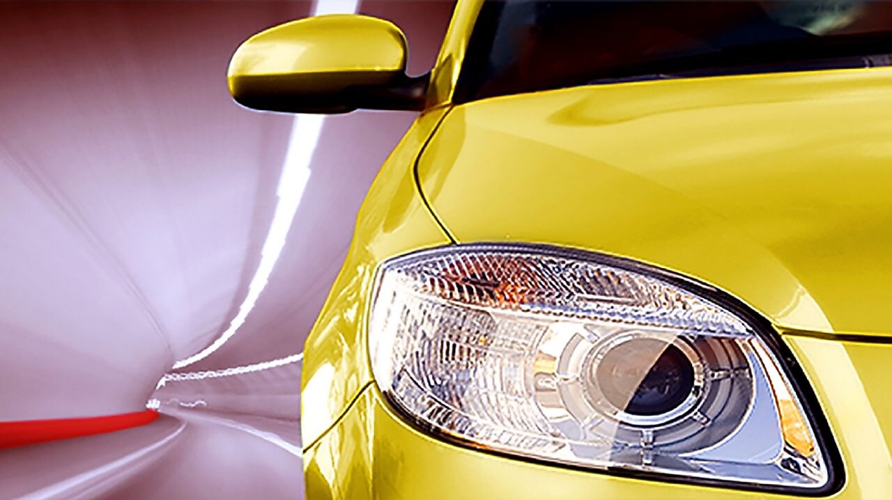 مقدمة سيارة صفراء تسير عبر نفق مع ضوء أمامي أيمن ومرآة جانبية