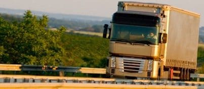 شاحنة تسير على طريق سريع على خلفية ريفية خضراء 