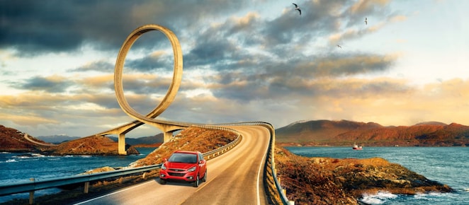 Red car driving on the road by the river