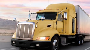 a yellow truck driving down a road at dusk