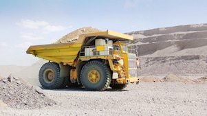yellow dumper truck driving through gravel