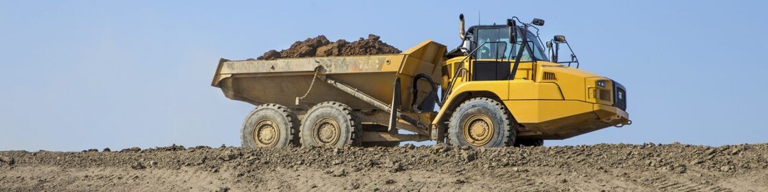 A worker in a yellow hard hat transposed onto a background og a road in some mountains