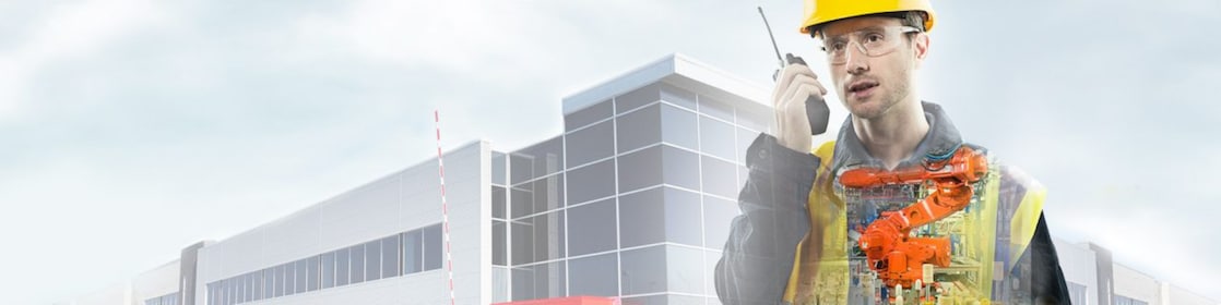 A man with yellow hard hat speaking into a radio transposed on a background showing a large building