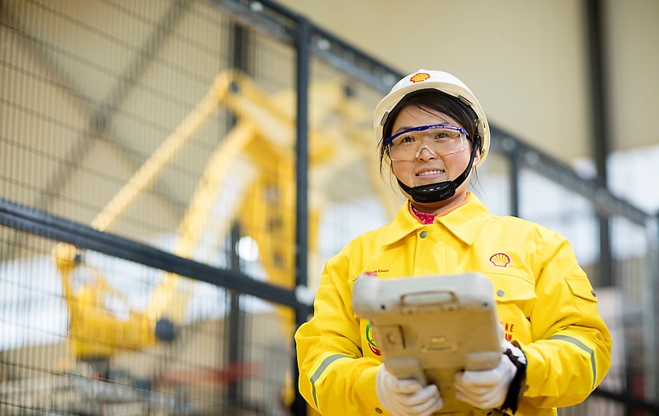 shell employee holding a remote control with a smile on her face