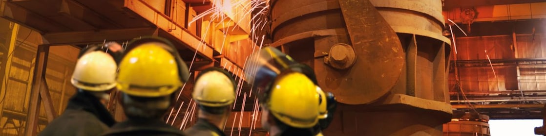 workers watching heavy machinery in a metal processing plant