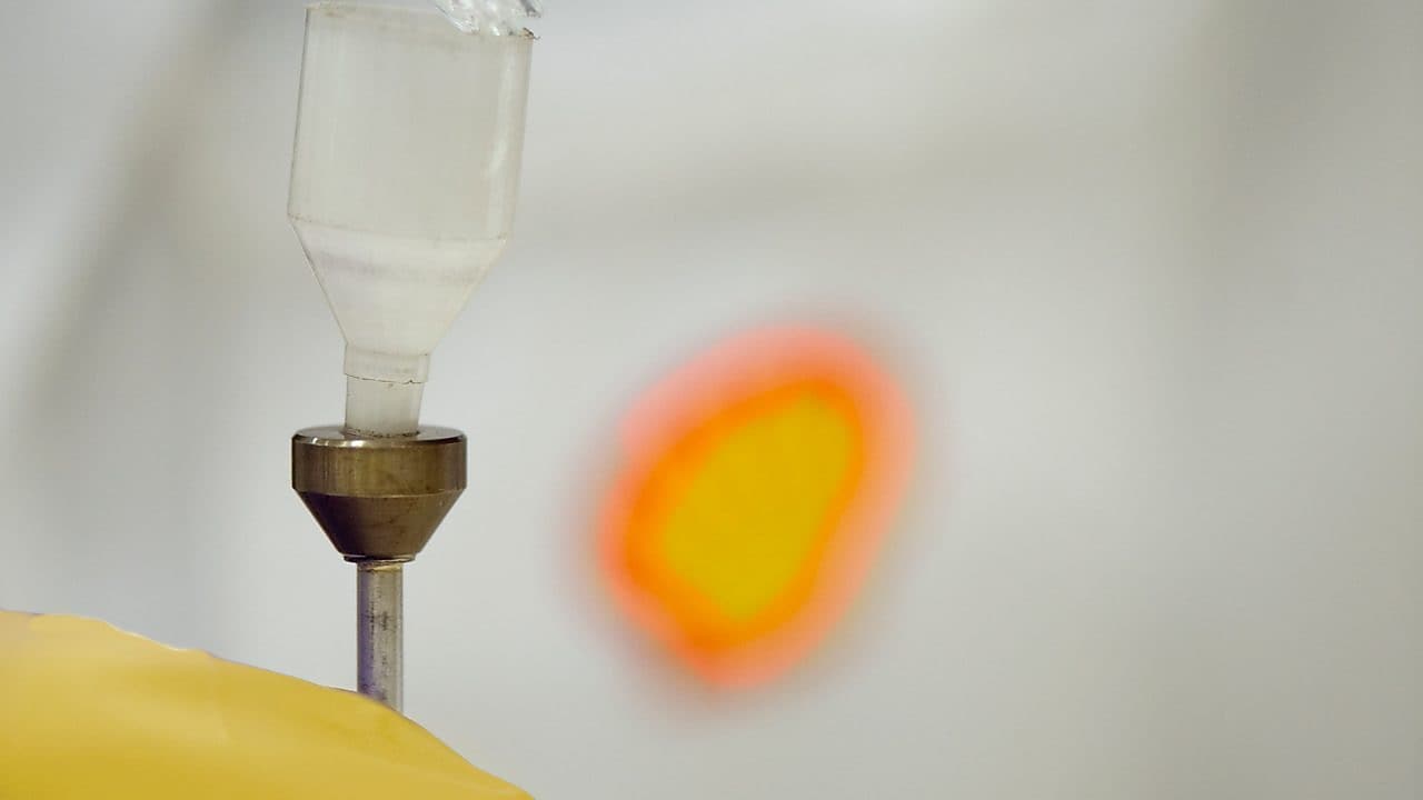 Liquid being poured into a plastic funnel by a shell scientist in a laboratory