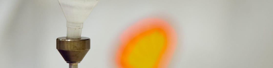 Liquid being poured into a plastic funnel by a shell scientist in a laboratory