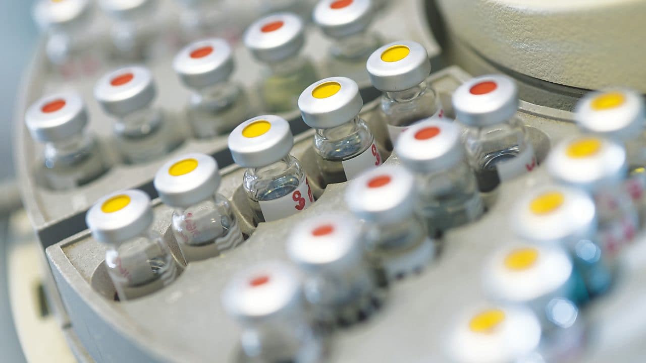 Rows of medicine vials sitting in a holder, some with red dots on the lid, and some with yellow dots on the lid
