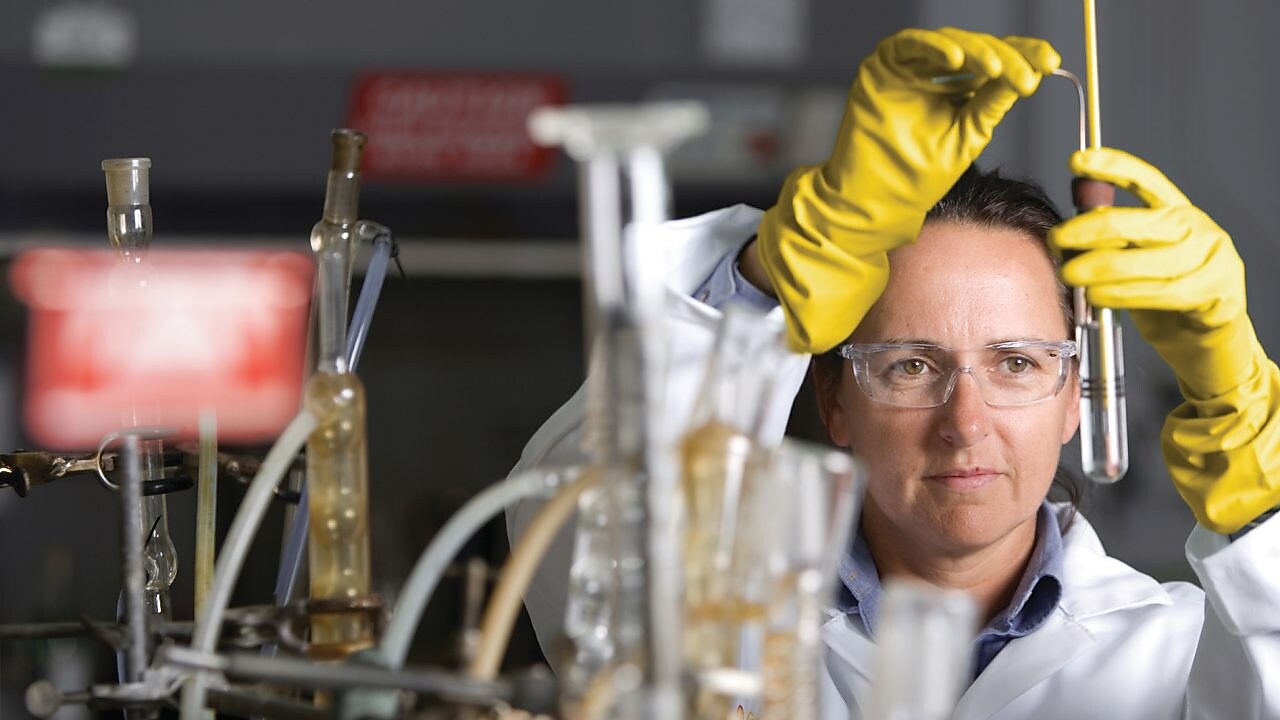lady in safety goggles conducting a lab experiment