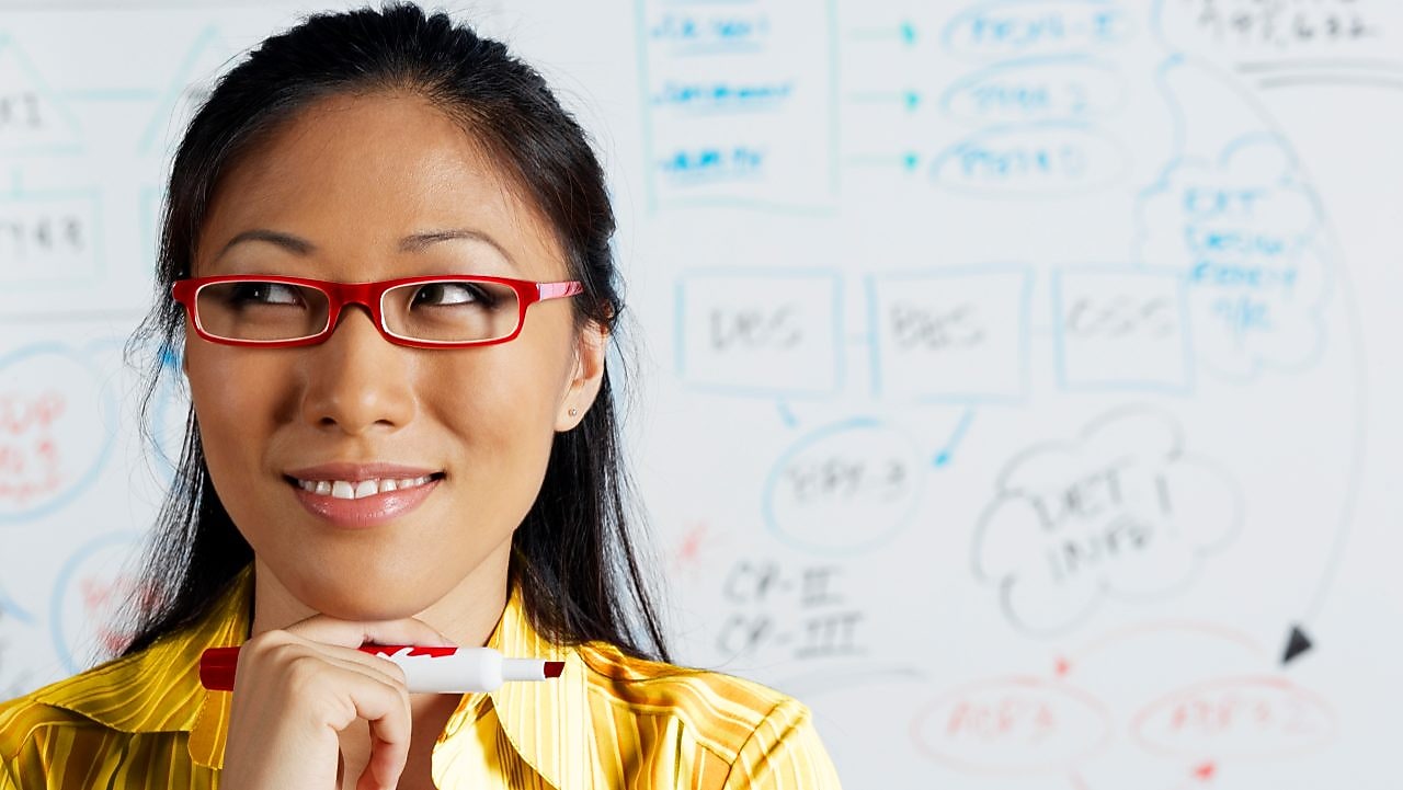 Close up of Asian businesswoman smiling in front of whiteboard