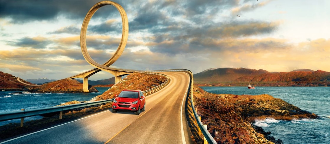 Red car driving on the road by the river